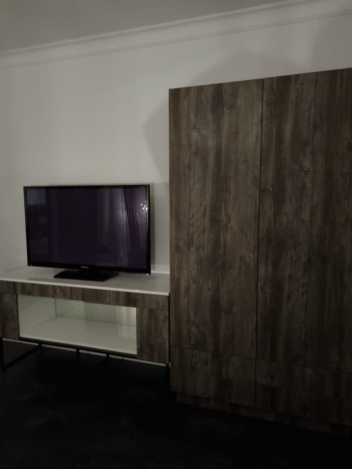 Dulap înalt în decor lemn închis, lângă comoda TV