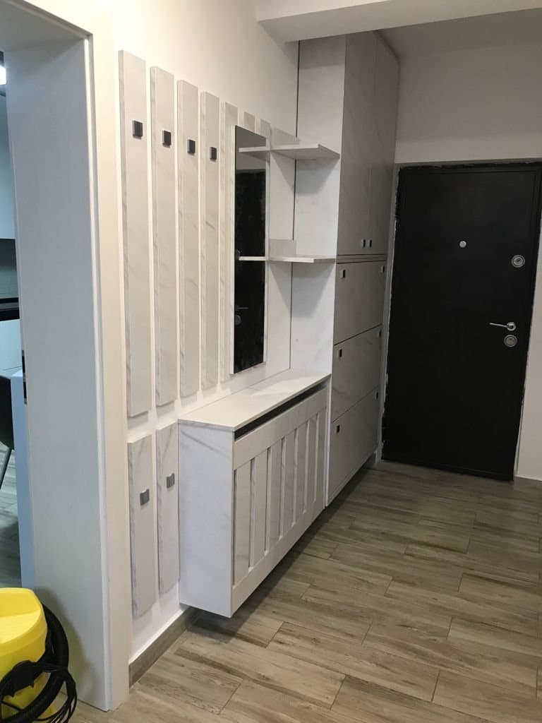 Hol cu panouri albe cu cuiere, mască de calorifer și dulapuri înalte